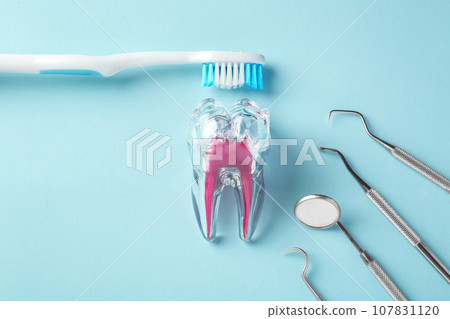 Dental care concept, tooth with toothbrush and dentist instruments on blue background, top view Dental care concept, tooth with toothbrush and dentist instruments on blue background, top view 107831120