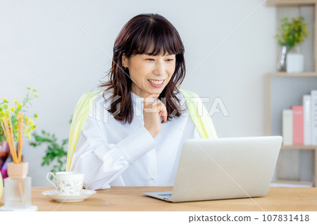 A woman using a computer in the living room A woman using a computer in the living room 107831418