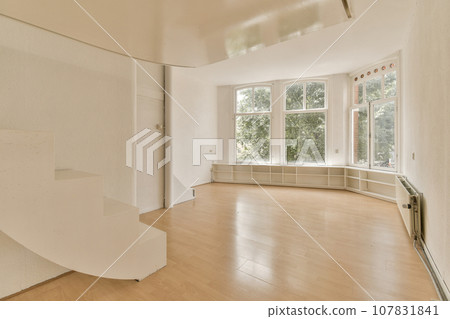 an empty living room with wood floors and white paint on the walls, there is a staircase leading up to the second floor an empty living room with wood floors and white paint on the walls, there is a staircase leading up to the second floor 107831841