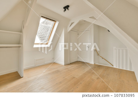 an empty room with wood flooring and skylights on the top of the attic loft windows are visible in the photo an empty room with wood flooring and skylights on the top of the attic loft windows are visible in the photo 107833095
