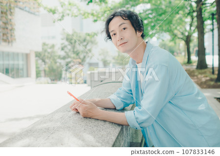 一名 30 多歲的男子在城市街道上使用智慧型手機 107833146
