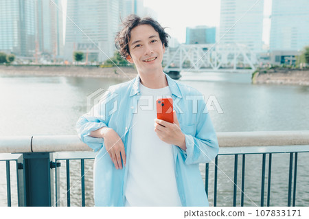 A man in his 30s using a smartphone on a city street 107833171