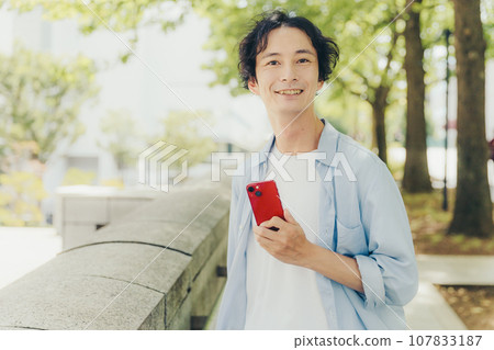 一名 30 多歲的男子在城市街道上使用智慧型手機 107833187