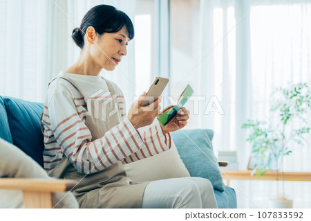 A housewife viewing a passbook 107833592