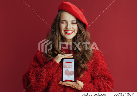 happy female with long wavy hair, smartphone and Valentine app 107834867