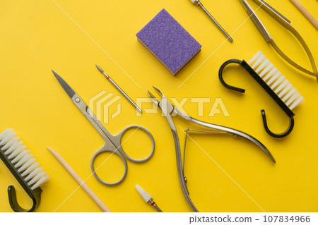 Professional manicure tools on yellow background. Manicure set. Top view. Cuticle pusher, cuticle trimmer and purpose scissor. Set of manicure and pedicure tools and cosmetics with space Professional manicure tools on yellow background. Manicure set. Top view. Cuticle pusher, cuticle trimmer and purpose scissor. Set of manicure and pedicure tools and cosmetics with space 107834966
