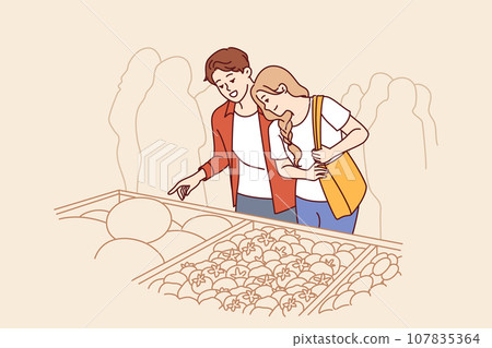 Man and woman do shopping at market and stand near crates of vegetables at farmers fair 107835364