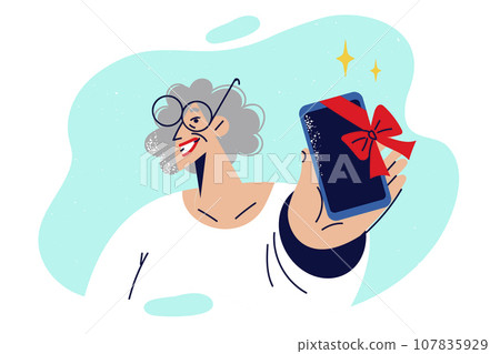 Elderly woman holds phone with gift ribbon and looks at screen smiling, showing present Elderly woman holds phone with gift ribbon and looks at screen smiling, showing present 107835929