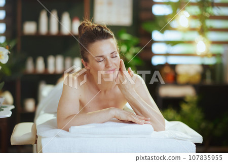 relaxed modern female in spa salon laying on massage table 107835955