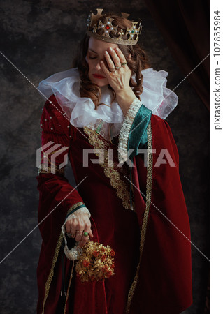 unhappy medieval queen in red dress with dried flower unhappy medieval queen in red dress with dried flower 107835984