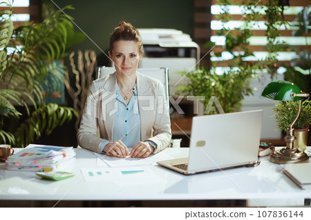 Portrait of woman worker in light business suit in green office 107836144