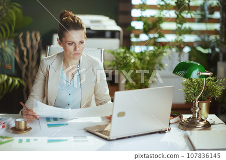 pensive woman employee in light business suit in green office 107836145