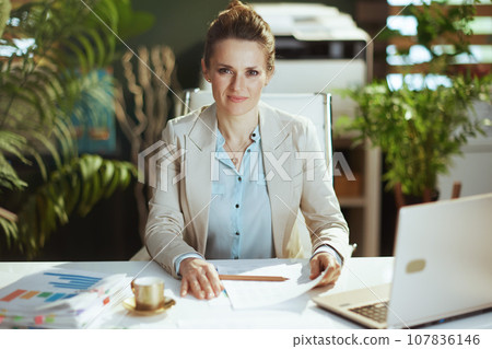 happy business woman in light business suit in green office 107836146