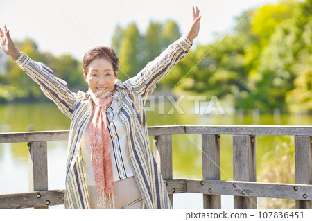 Senior woman walking by the pond Senior woman walking by the pond 107836451