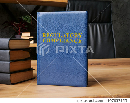 Regulatory compliance laws next to stack of books. 107837155