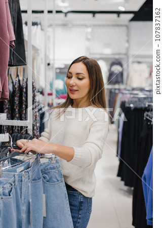 Woman choosing jeans in clothing store in the mall 107837162
