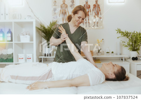 happy female therapist in massage cabinet doing checkup 107837524