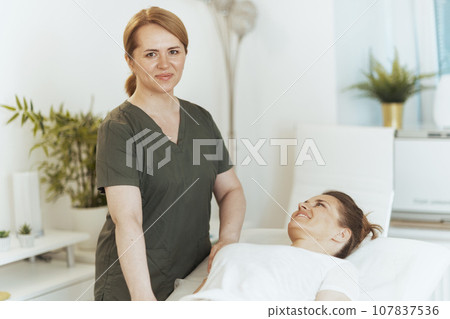 female therapist in massage cabinet conducting examination female therapist in massage cabinet conducting examination 107837536