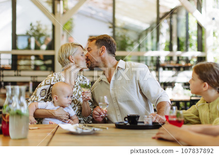 Family with daughter and small baby at family dinner in restaurant. A small family celebration in family friendly restaurant. Family with daughter and small baby at family dinner in restaurant. A small family celebration in family friendly restaurant. 107837892
