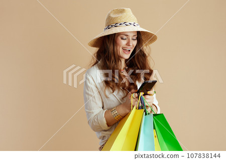 smiling trendy woman in blouse and shorts isolated on beige 107838144