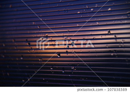 Blue-purple polycarbonate with raindrops. View of wet glass in the setting sun. 107838389