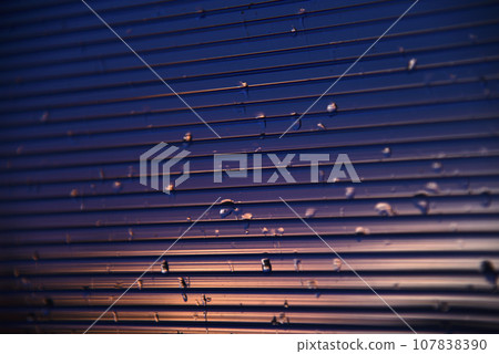 Blue-purple polycarbonate with raindrops. View of wet glass in the setting sun. 107838390