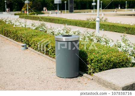 Public metal gray trash can in Park on city street outdoors. Help to reduce waste, Help global warming. High quality photo Public metal gray trash can in Park on city street outdoors. Help to reduce waste, Help global warming. High quality photo 107838716
