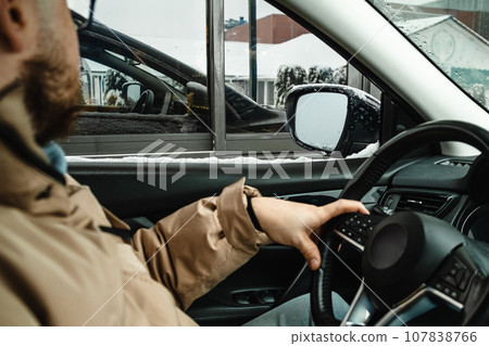 the man is waiting for his silence while sitting in the car by driving through or drive thru the man is waiting for his silence while sitting in the car by driving through or drive thru 107838766