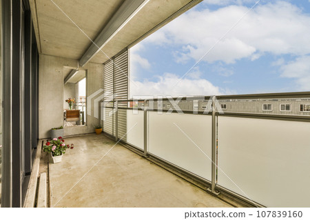 a balcony with white walls and grey metal railings on the right side, looking out onto the street below 107839160