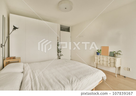 a bedroom with a bed, dresser and cabinetd cupboards in the same color as they appear on the wall 107839167