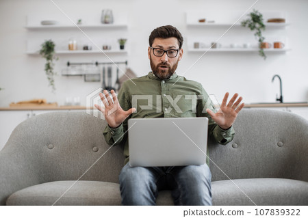 Male freelancer using laptop for video call at home 107839322