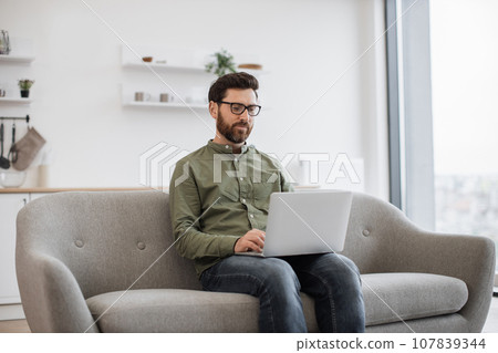 Focused man working on laptop while staying at home Focused man working on laptop while staying at home 107839344