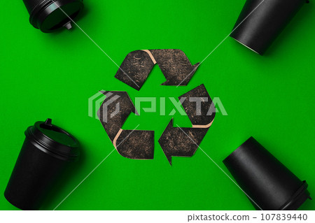 Disposable coffee cup and recycling sign on green background Disposable coffee cup and recycling sign on green background 107839440