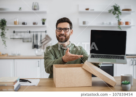 Male blogger doing unpacking of new portable laptop at home Male blogger doing unpacking of new portable laptop at home 107839454