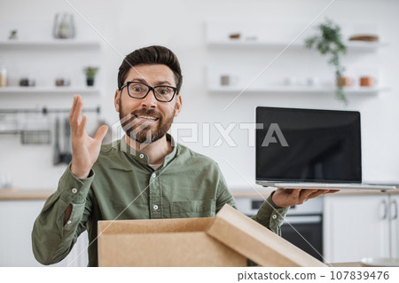 Male blogger doing unpacking of new portable laptop at home 107839476