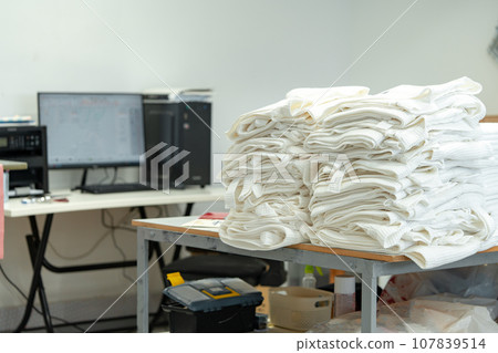 Folded and rolled fabrics on wooden shelf in tailor workshop Folded and rolled fabrics on wooden shelf in tailor workshop 107839514
