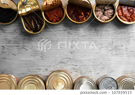 Top view of opened cans with fish conserves on wooden background Top view of opened cans with fish conserves on wooden background 107839515