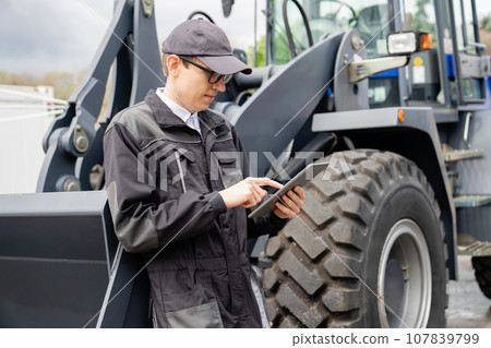 Serviceman with digital tablet on a background of the tractor 107839799
