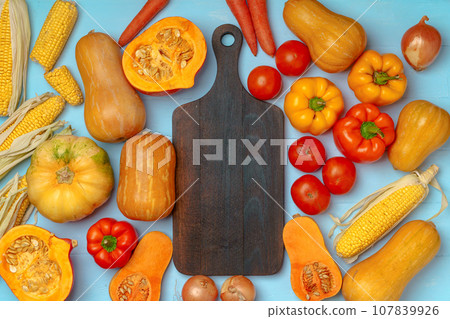 Autumn background with fresh vegetables and wooden cutting board Autumn background with fresh vegetables and wooden cutting board 107839926