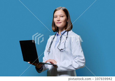 Young woman doctor, medical student with laptop on blue background 107839942