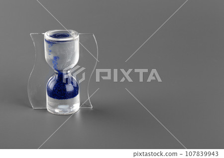 Blue hourglass on gray background close up 107839943