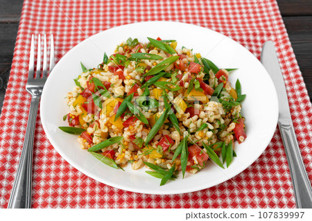 Georgian Tabbouleh salad with bulgur and vegetables on black wooden table Georgian Tabbouleh salad with bulgur and vegetables on black wooden table 107839997