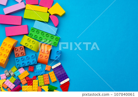Multicolored pieces of toy constructor on blue background Multicolored pieces of toy constructor on blue background 107840061