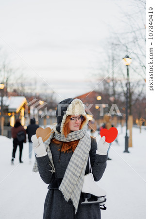 young beautiful woman is holding red card in form of heart, Valentine's day young beautiful woman is holding red card in form of heart, Valentine's day 107840419
