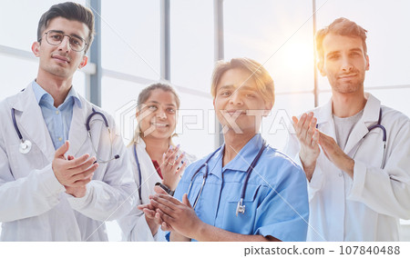 Portrait of multicultural medical team cheering in hospital corridor 107840488