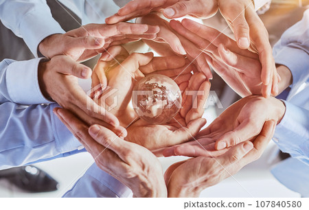 Many different hands are holding planet Earth. 107840580