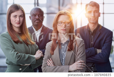 Business people stand with each other in a conference room with their arms crossed 107840835