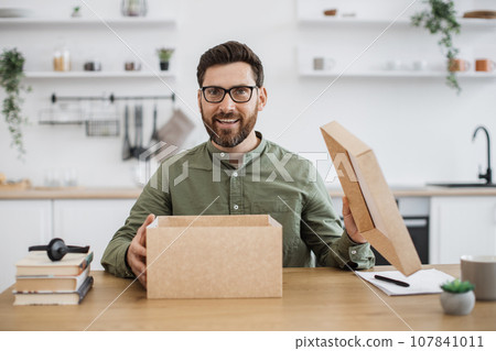 Technology blogger sitting at desk and opening cardboard box 107841011