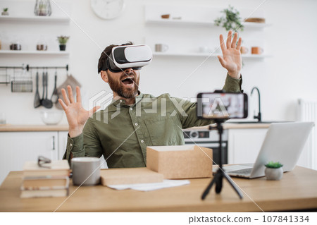 Blogger reviewing VR headset and recording video on mobile Blogger reviewing VR headset and recording video on mobile 107841334