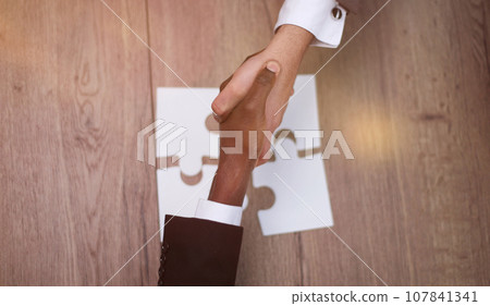 Diverse team people assembling jigsaw puzzle, multiracial group of black and white colleagues engaging in succes Diverse team people assembling jigsaw puzzle, multiracial group of black and white colleagues engaging in succes 107841341